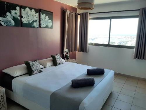 Schlafzimmer mit einem großen weißen Bett und einem Fenster in der Unterkunft Stay In Tahiti- Bel F3 moderne avec magnifique vue Panoramique sur Papeete in Papeete