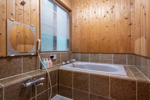 a bathroom with a tub with wooden walls and a window at S-villa Nasu 7th in Nasu