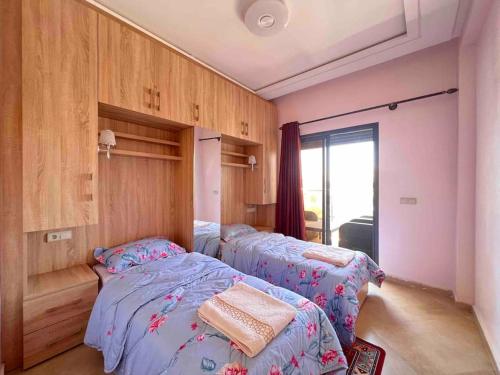 two twin beds in a room with pink walls at Beachfront surfers paradise in Aourir