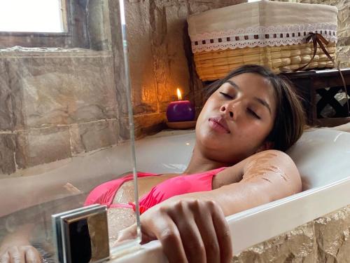 eine Frau, die in einer Badewanne liegt in der Unterkunft Treehouse Gastro Hotel in Quito