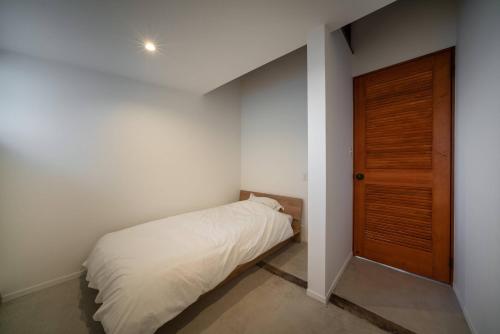 a small bedroom with a bed and a wooden door at THE SECOND Kujukuri Beach House in Kujukuri