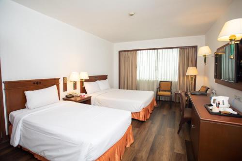 a hotel room with two beds and a desk at Ramada by Wyndham D MA Bangkok in Bangkok