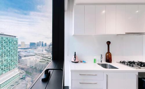 biała kuchnia z widokiem na miasto w obiekcie Prima Tower 1B Apt by GoodLive w Melbourne
