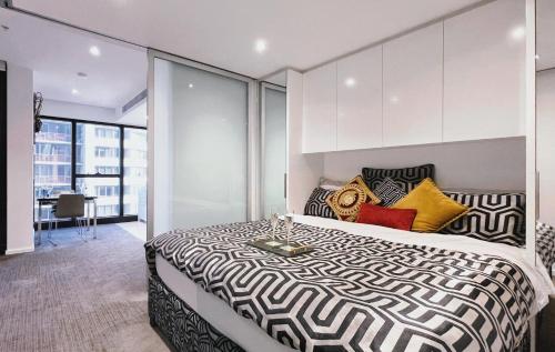 1 dormitorio con 1 cama grande con almohadas amarillas y negras en Prima Tower 1B Apt by GoodLive, en Melbourne