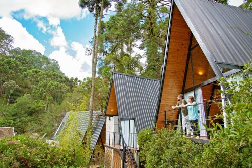 a man and woman standing on the balcony of a house at Chalé Mon Amour, puro design no ar puro in Campos do Jordão