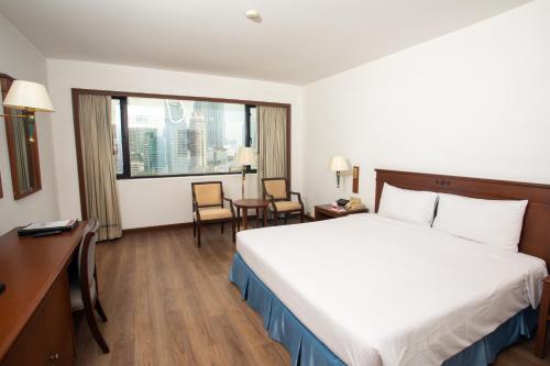 a hotel room with a bed and a desk and a window at Ramada by Wyndham D MA Bangkok in Bangkok