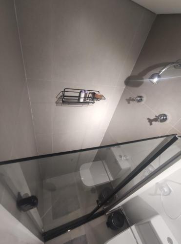 uma prateleira de vidro na casa de banho com um lavatório em Studio Perdizes em São Paulo