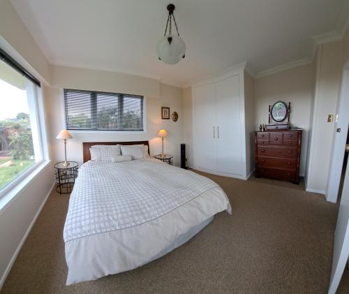 1 dormitorio con 1 cama, vestidor y ventana en Grange Harbour View B&B, en Tauranga