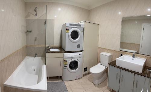 a bathroom with a washing machine and a toilet at Bundled Bliss 2 bedroom Condo in Adelaide CBD in Adelaide