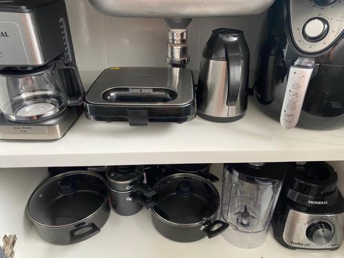 a shelf with pots and pans and a coffee maker at Apto refúgio 101 em São Luís/MA (inteiro) in São Luís