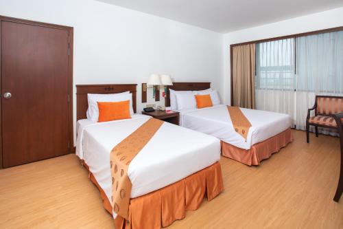 a hotel room with two beds and a chair at Ramada by Wyndham D MA Bangkok in Bangkok