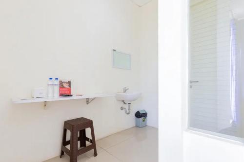 a white bathroom with a sink and a stool at RedDoorz @ Bukit Palma Surabaya in Kendung