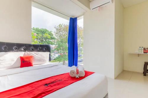 a bedroom with a large window and a bed with slippers at RedDoorz @ Bukit Palma Surabaya in Kendung