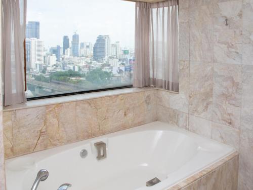 a bath tub in a bathroom with a window at Ramada by Wyndham D MA Bangkok in Bangkok
