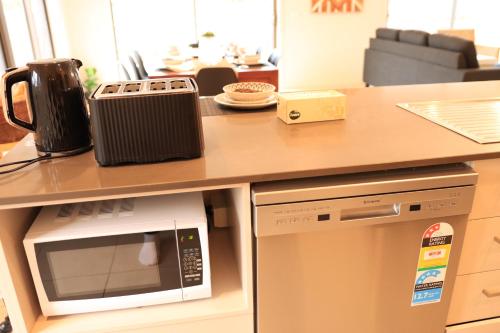 a kitchen with a counter with a microwave and a refrigerator at Melbourne holiday house for 15 peoples in Sanctuary Lake in Point Cook