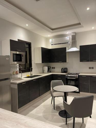 uma cozinha com armários pretos e uma mesa e cadeiras em شقة نيرفانا ريزدنس Nirvana Residence Apt em Riyadh