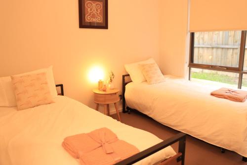 two beds in a room with a window at Melbourne holiday house for 15 peoples in Sanctuary Lake in Point Cook