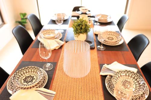 a long wooden table with plates and wine glasses at Melbourne holiday house for 15 peoples in Sanctuary Lake in Point Cook