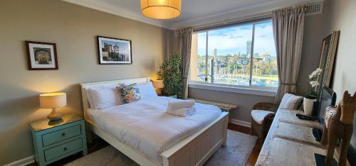 Harbourfront Bliss - 2 bedrooms, parking, balcony في سيدني: غرفة نوم صغيرة بها سرير ونافذة