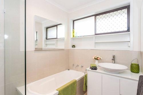 ein Badezimmer mit einer weißen Badewanne und einem Waschbecken in der Unterkunft Torquay Retreats Aus- TwentyTwo Pride in Torquay