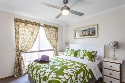 ein Schlafzimmer mit einem grünen und weißen Bett und einem Fenster in der Unterkunft Torquay Retreats Aus- TwentyTwo Pride in Torquay