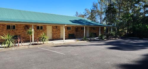 a building with a green roof and a parking lot at Golf Club Motor Inn Wingham in Wingham