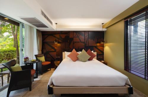 a bedroom with a bed and a desk and a window at U Inchantree Kanchanaburi in Kanchanaburi