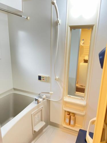 a bathroom with a shower and a tub and a mirror at Cocostay The Peace Memorial Park ココステイ平和記念公園 Excellent location overlooking Peace Park! in Hiroshima