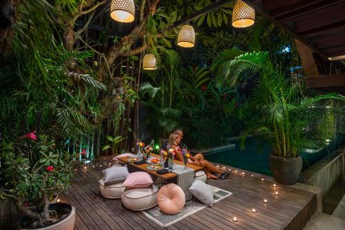 a woman sitting on a deck in a garden at The Kemilau Hotel & Villa Canggu Bali in Canggu