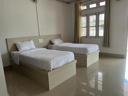 two twin beds in a room with two windows at Hotel Anne Ziro in Hāpoli