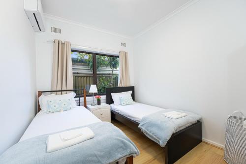 2 aparte bedden in een kamer met een raam bij Belmore Brand new renovated 3Br house AC & Parking in Sydney