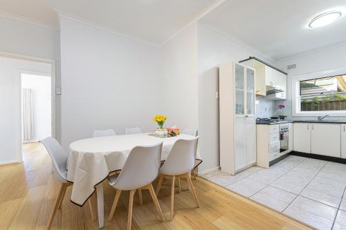 a white dining room with a white table and chairs at Belmore Brand new renovated 3Br house AC & Parking in Sydney