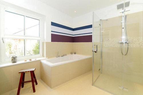 uma casa de banho com uma banheira e um chuveiro em vidro. em Apartments, Wyk auf Foehr em Wyk auf Föhr