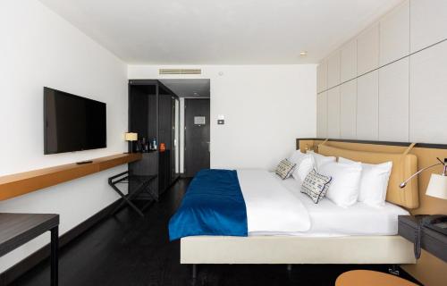 a hotel room with a bed and a flat screen tv at Crowne Plaza Belgrade by IHG in Belgrade