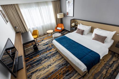 a hotel room with a large bed and a chair at Crowne Plaza Belgrade by IHG in Belgrade