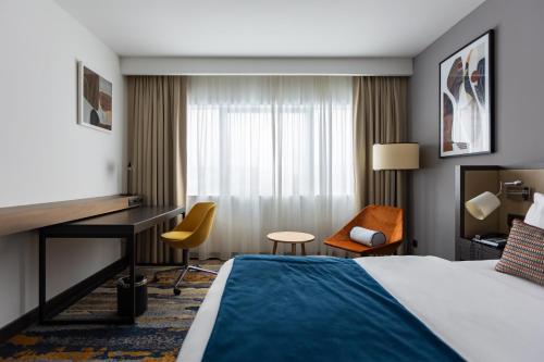 a hotel room with a bed and a desk and chairs at Crowne Plaza Belgrade by IHG in Belgrade