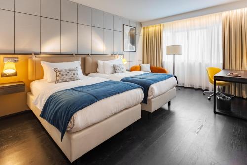 a hotel room with two beds and a desk at Crowne Plaza Belgrade by IHG in Belgrade