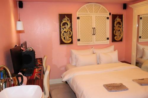 a bedroom with a bed and a desk with a television at Hotel Marigold in Incheon