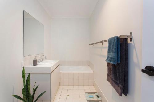 Baño blanco con lavabo y espejo en Suburban Villa, en Perth