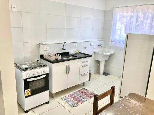 uma pequena cozinha com um fogão e um lavatório em Apartamento Privado - 2 quartos, varanda, sala e cozinha integrada em Piracicaba