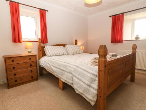 a bedroom with a bed and a dresser and two windows at Porth Awyr in Llangwnadl
