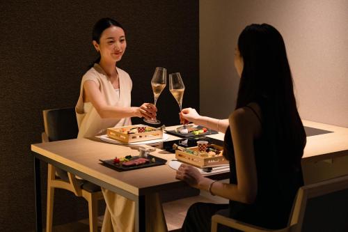 two women sitting at a table with glasses of wine at Urari Takeo Garden Terrace Spa Resorts in Takeo
