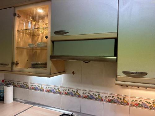una cocina con un armario de cristal con platos. en Can Ginesta Muy feliz&tranquilo, en Barcelona