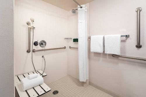 a bathroom with a shower with a bench and towels at Courtyard Sacramento Rancho Cordova in Rancho Cordova