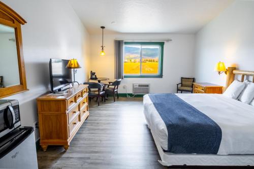 a bedroom with a bed and a television and a table at Teton Valley Motel in Victor
