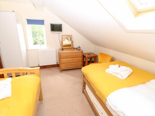 a attic bedroom with two beds and a tv at The Barn in Northallerton