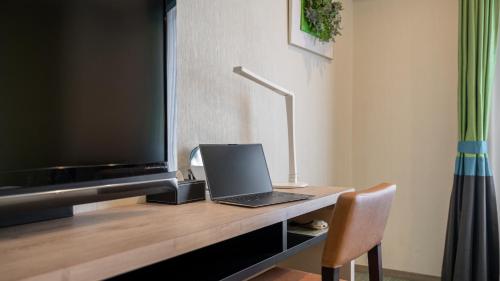 a laptop sitting on a desk next to a television at New Otani Inn Sapporo in Sapporo