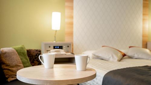 a hotel room with a bed and two cups on a table at New Otani Inn Sapporo in Sapporo