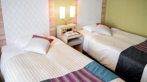 a hotel room with two beds and a table at New Otani Inn Sapporo in Sapporo