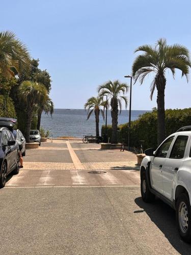 two cars parked in a parking lot next to the ocean at Le Castello in Saint-Aygulf